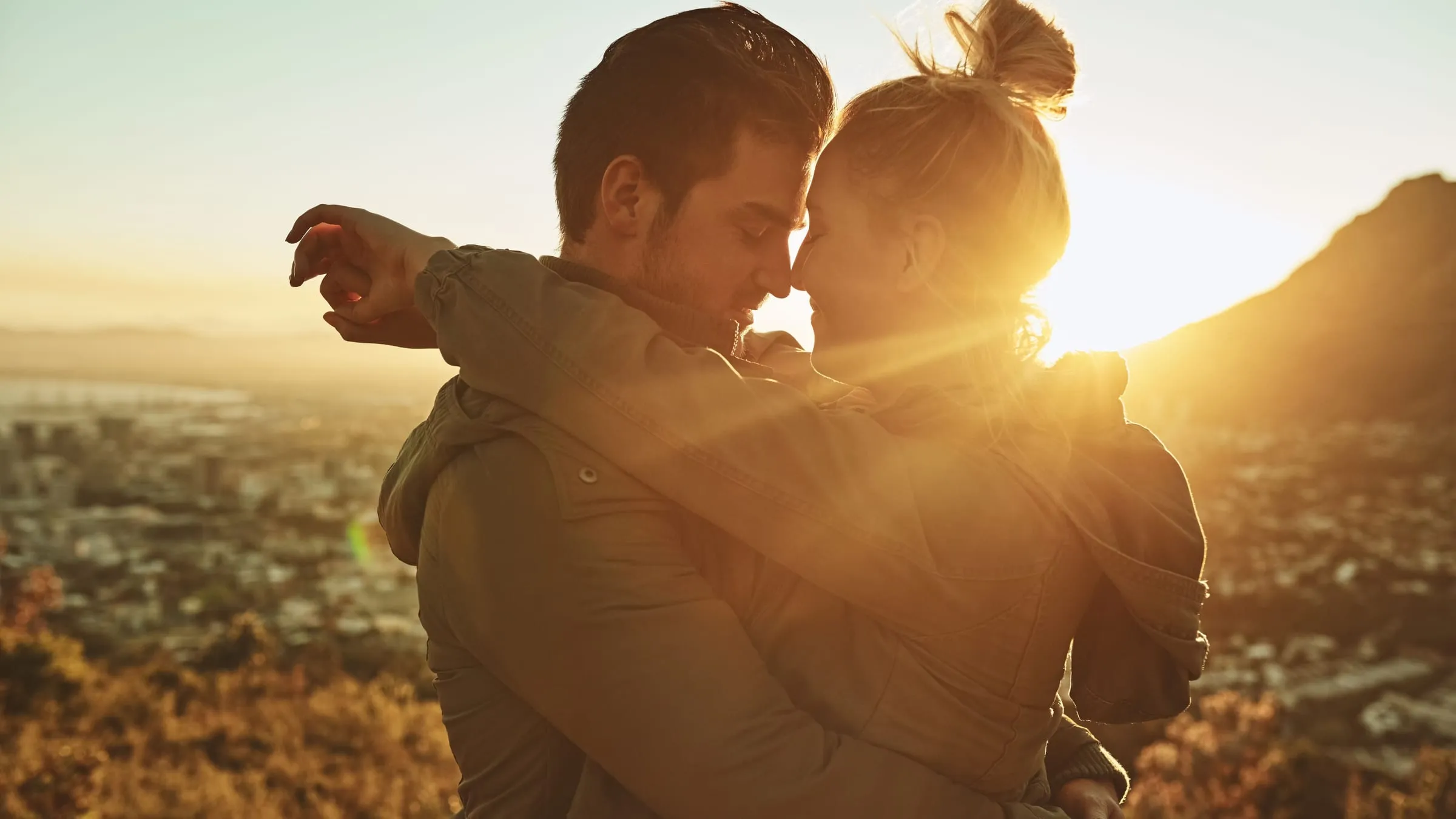 Do soulmates exist? A couple embracing on a hillside at sunset, their foreheads touching