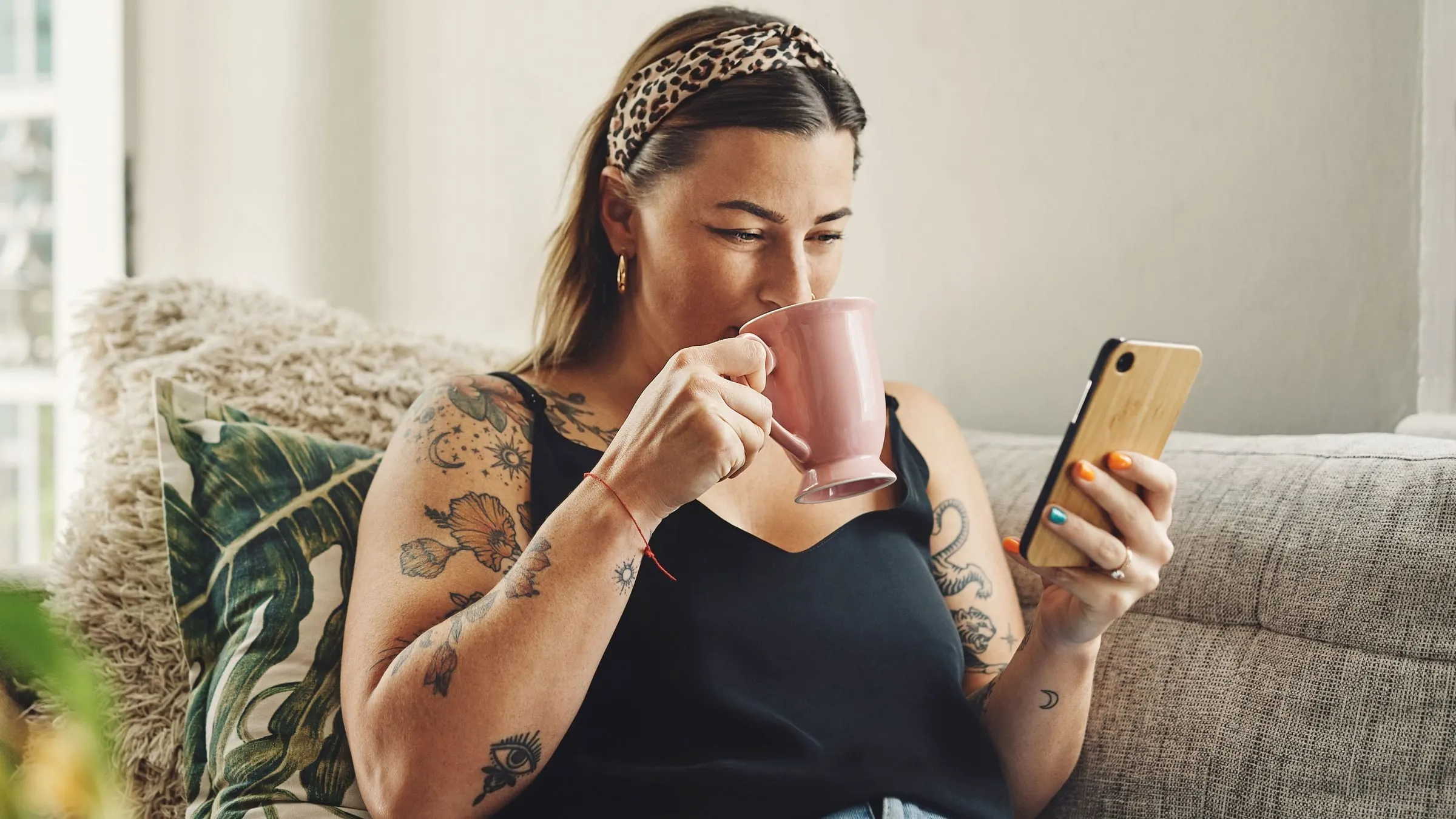 Hint soulmate sketch: a woman on a sofa looks at the app on her phone while she drinks from a pink mug