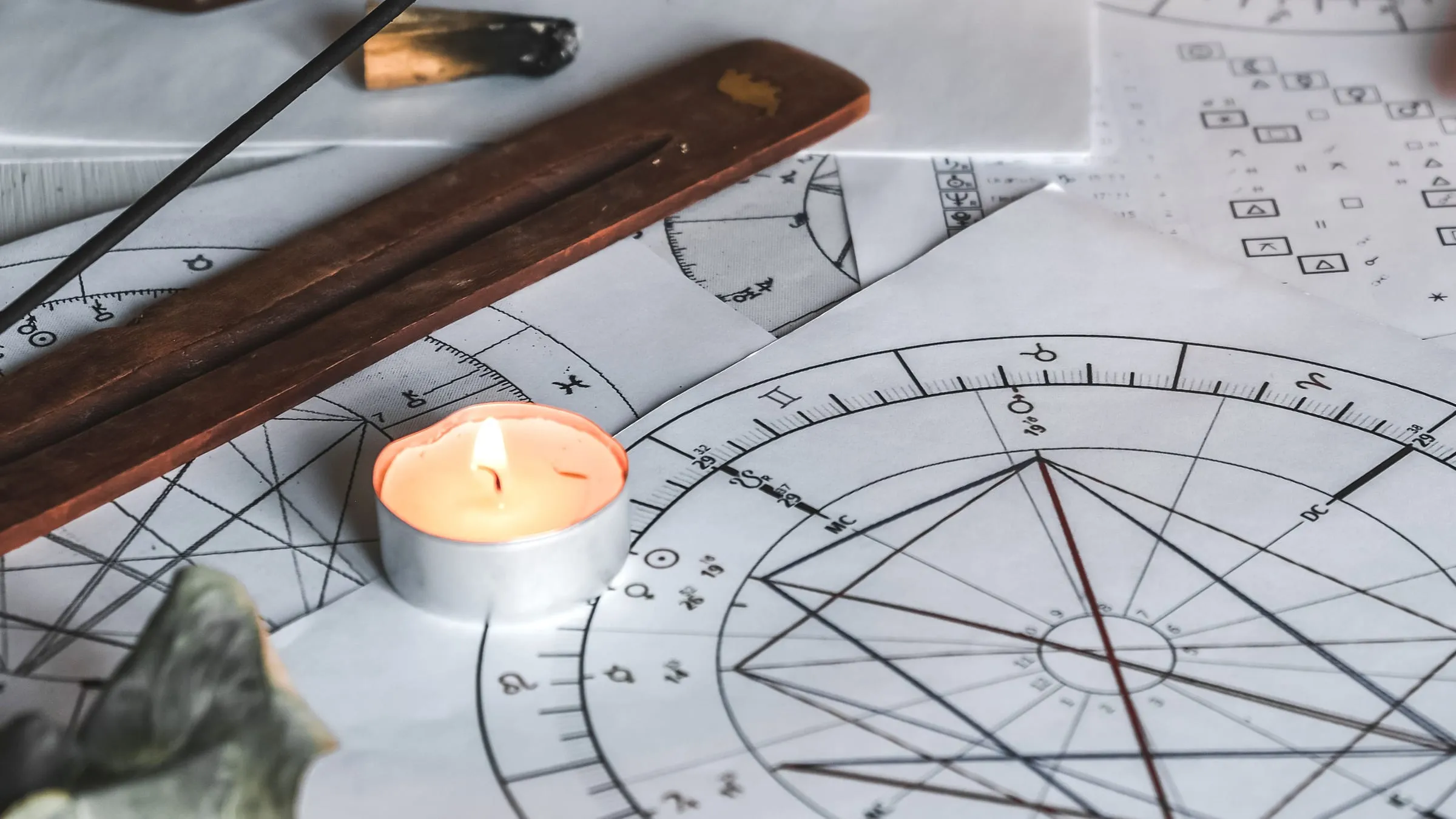 Soulmate by birth date: printed birth charts on a table with a lit tea light and an incense holder