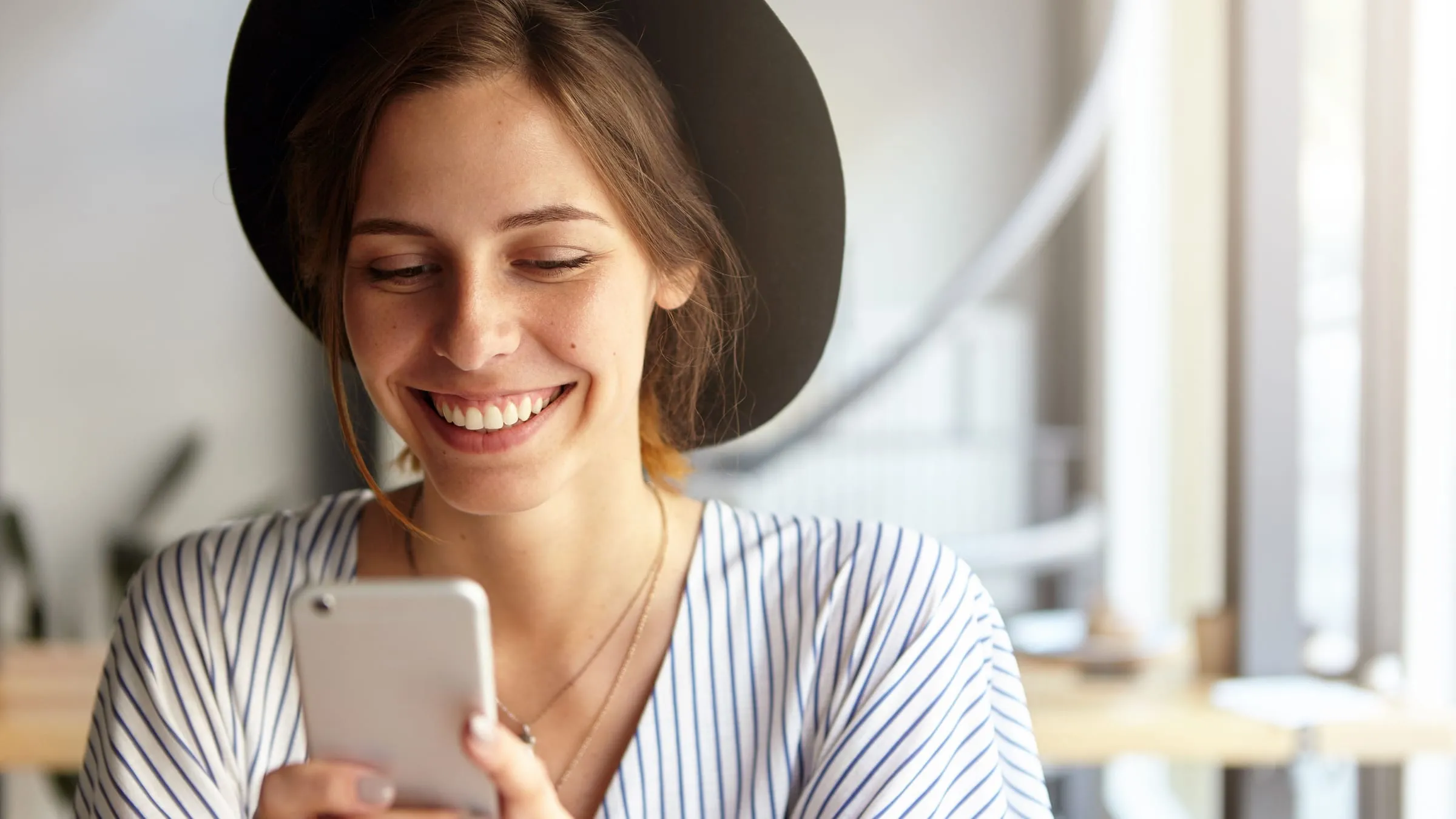 Nebula soulmate sketch and similar apps: a woman in a wide-brimmed hat smiling at the phone in her hands