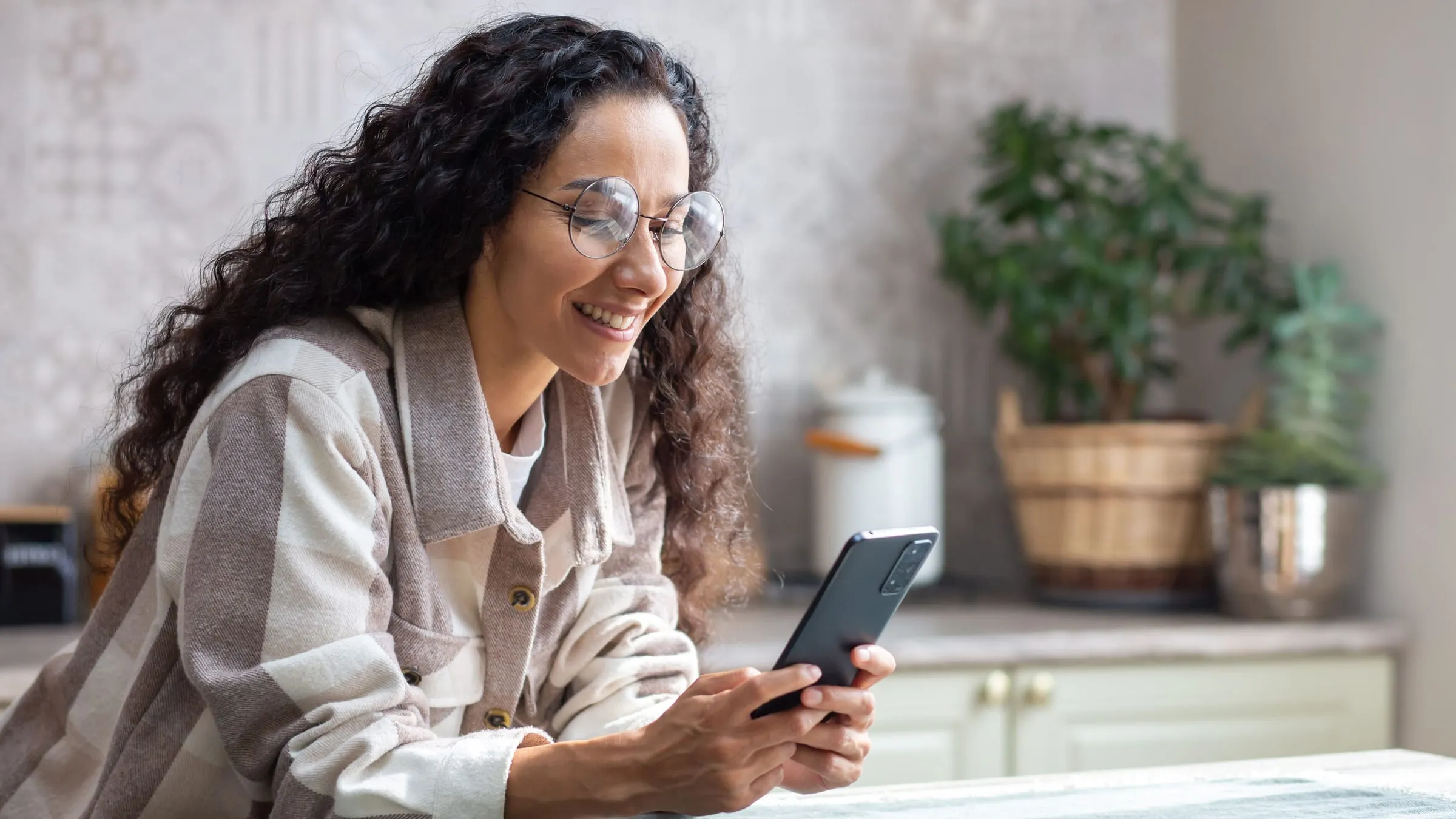 Soulmate sketch filter: a woman with curly hair and glasses smiling at her phone at a kitchen table