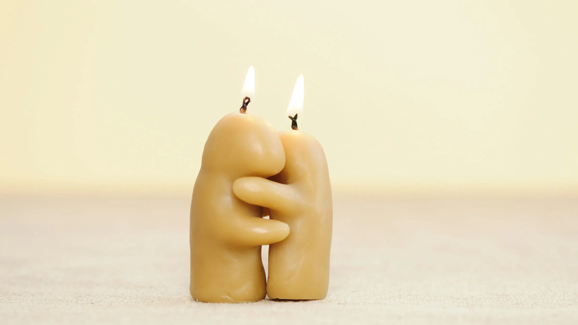 Twin flame vs soulmate: two beeswax figures with lit wicks, standing with their arms around each other