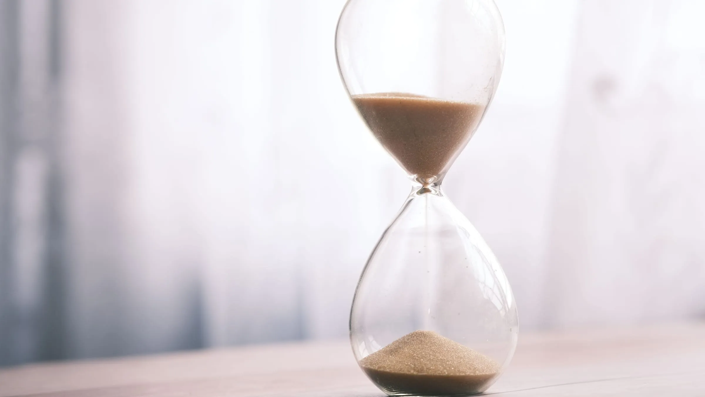 When will I meet my soulmate? An hourglass with sand running through it in soft window light